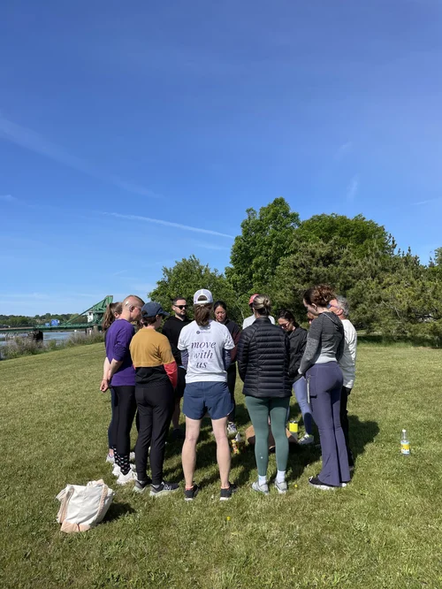 A grief movement group gathered together outdoors, one wearing a 'move with us' shirt